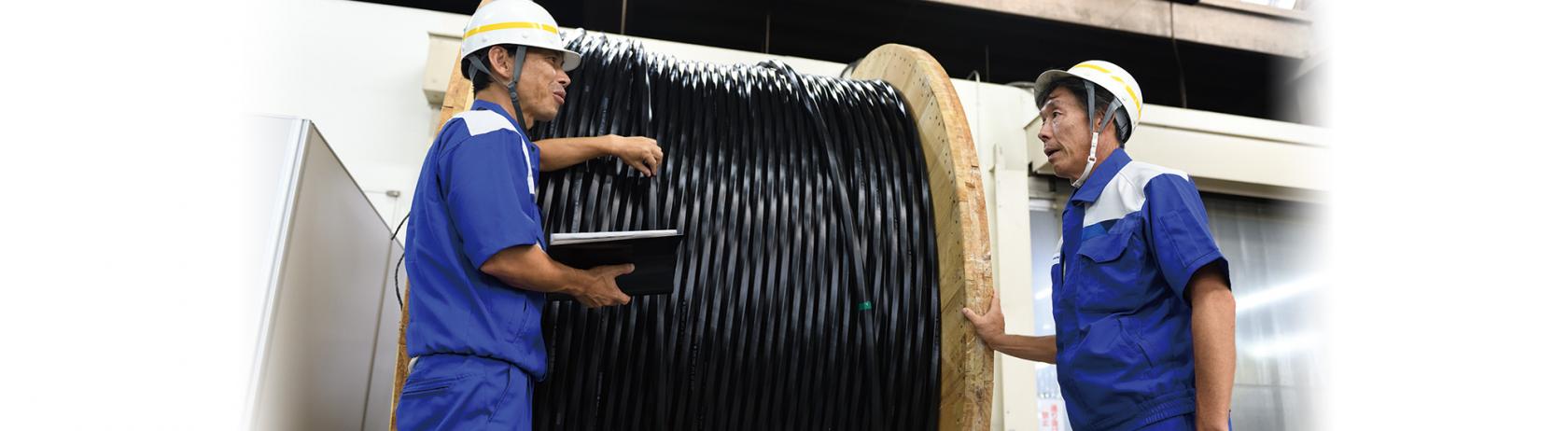 3456-fiber-count optical cable awaiting shipment (left: Takehiko Okada, General Manager of the Cable Manufacturing Dept., right: Tsuguo Amano, General Manager of the Engineering Dept.)