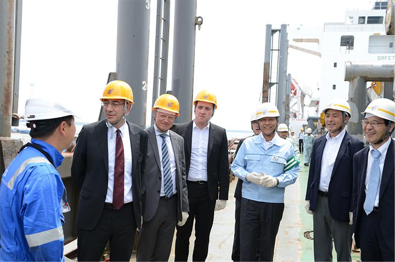 Inspection tour members from the Belgian company Elia watch the systematically performed shipping work, guided by Takahiro Nakano (third from left), Managing Executive Officer and Shinya Asai (far right), General Manager, Nemo Link Project Office of Sumitomo Electric.